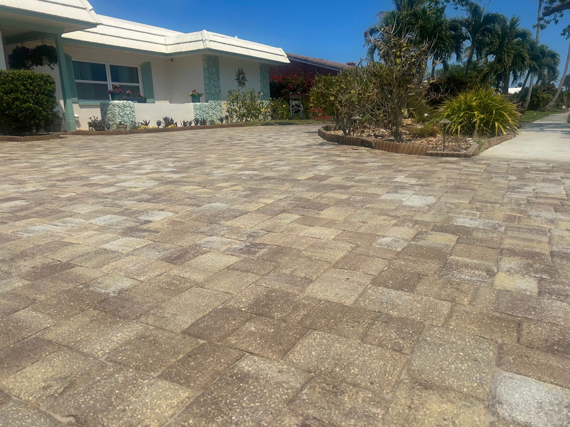 Sealed driveway beside ranch home — paver work by Atlantic Exteriors in Brevard County, FL