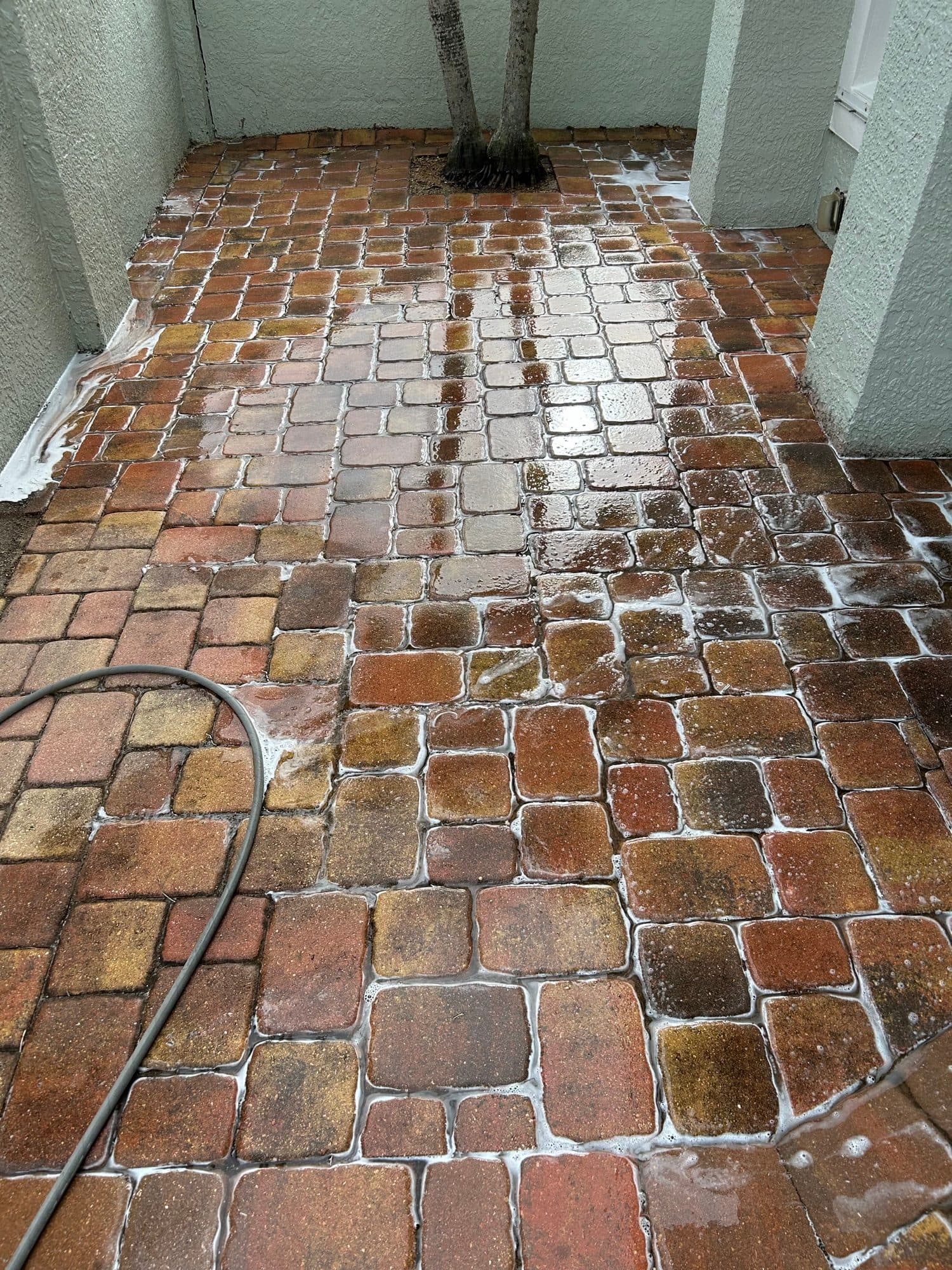 Wet cobble courtyard mid-wash — paver work by Atlantic Exteriors in Brevard County, FL