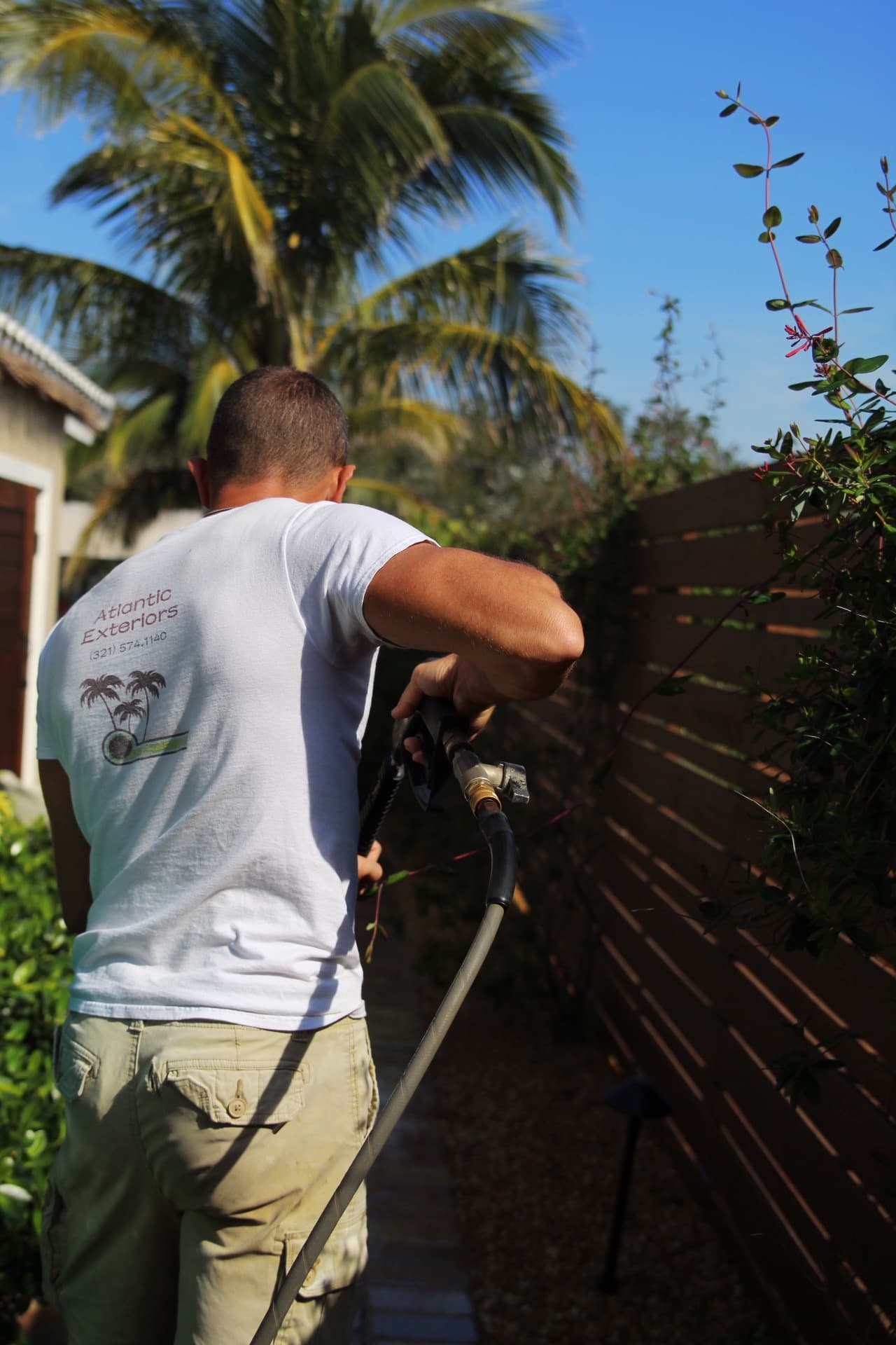 Derek sealing a walkway along the fence line — paver work by Atlantic Exteriors in Brevard County, FL