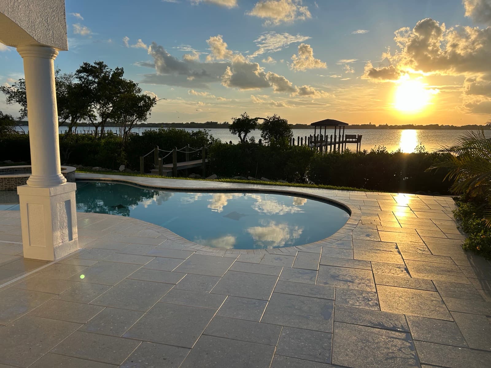 Waterfront travertine pool deck at sunset — paver work by Atlantic Exteriors in Brevard County, FL